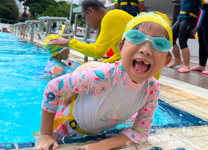 a happy child attending a group swimming lesson for kids