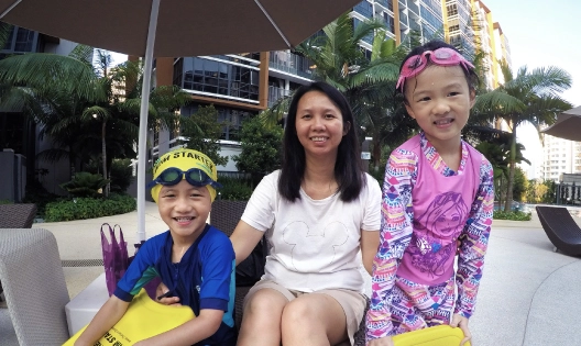 Children wearing swimming costume and goggles sitting with their mother
